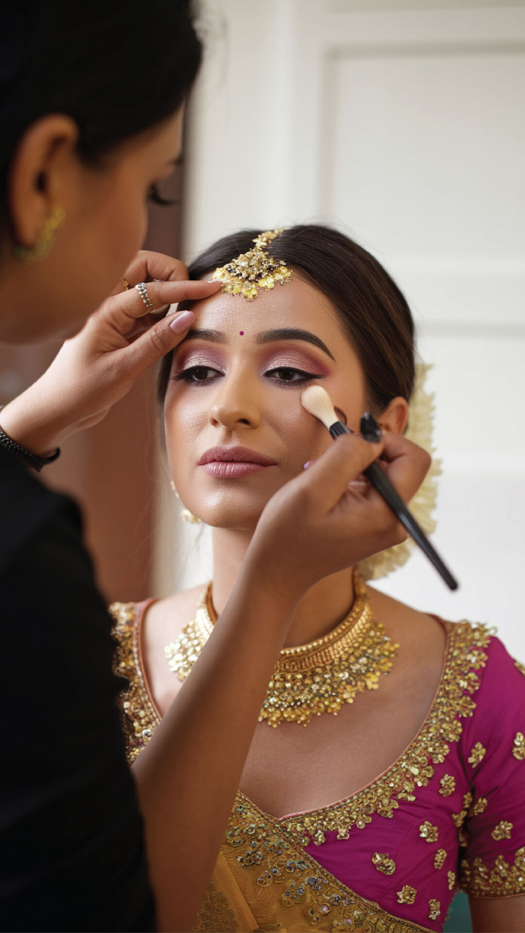 A bride-to-be getting her flawless engagement makeup done by a skilled professional artist at a salon.